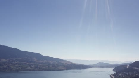 Aerial-panaramic-upwards-camera-from-bird-eye-view-to-sparking-gleaming-sunligt-on-a-hot-sunny-summer-day-in-a-lake-valley-with-mountains-cottage-country-hemp-vbeverage-industry-hiking-cycling-hybrid