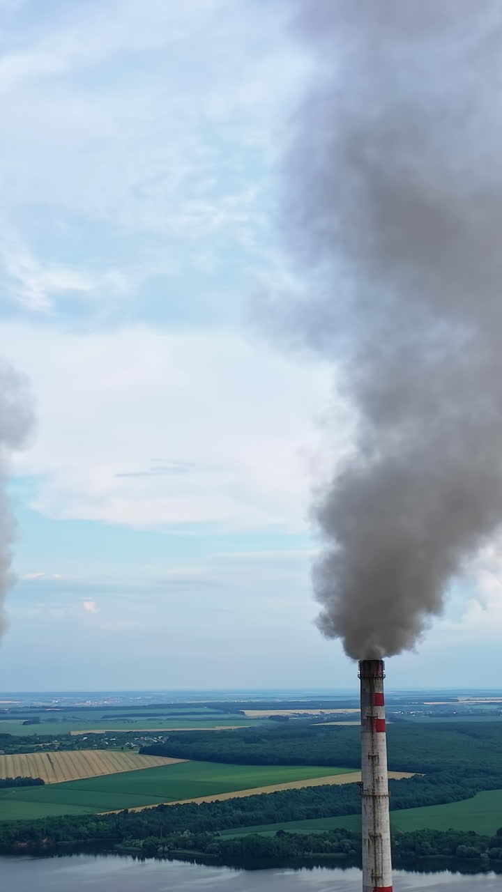 Atmospheric air pollution from industrial smoke. Pipes with chemical smoke from industrial plant. Thick smoke and steam pollute the environment. Climate change and global warming. Vertical video
