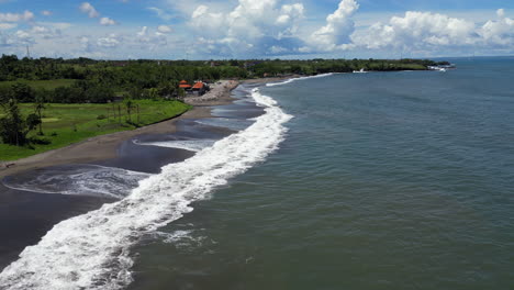 empty bali beach as drone tracks out over waves in indonesia