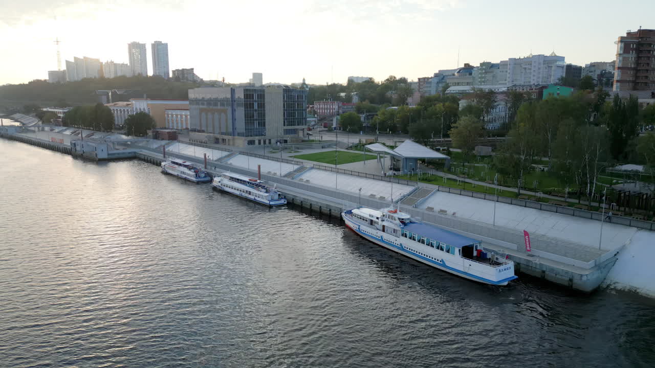 Boats docked at a modern city embankment along a river with buildings in the background