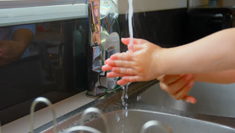 close-up of mother and daughter washing hands in sink at comfortable home 4k