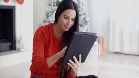 una mujer sonriente informándose en sus redes sociales.