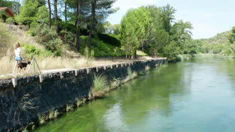 young woman walking her dog along the river bank