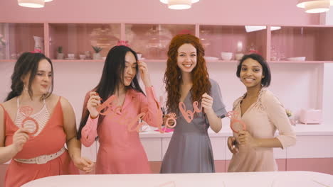 four  women with headdresses and holding cardboard phrase