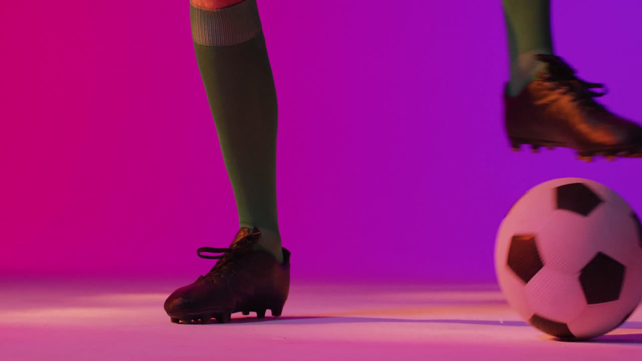 Calciatore caucasico con pallone da calcio su illuminazione rosa neon
