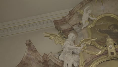 sculptures of angels with golden wings on a baroque altar in a church, picture of god in the middle