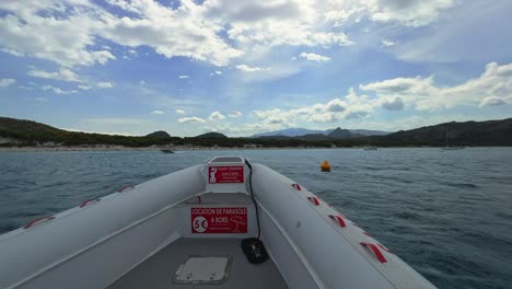 first-person view of bow of tour boat sailing toward famous pristine saleccia beach in corsica, france