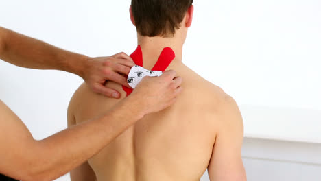 physiotherapist applying red kinesio tape to patients back