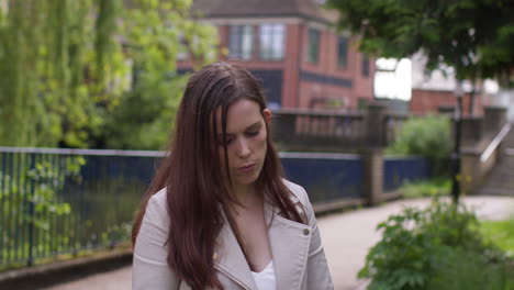 stressed and worried woman outdoors with financial worries about cost of living crisis debt and paying bills looking at mobile phone in city park 1