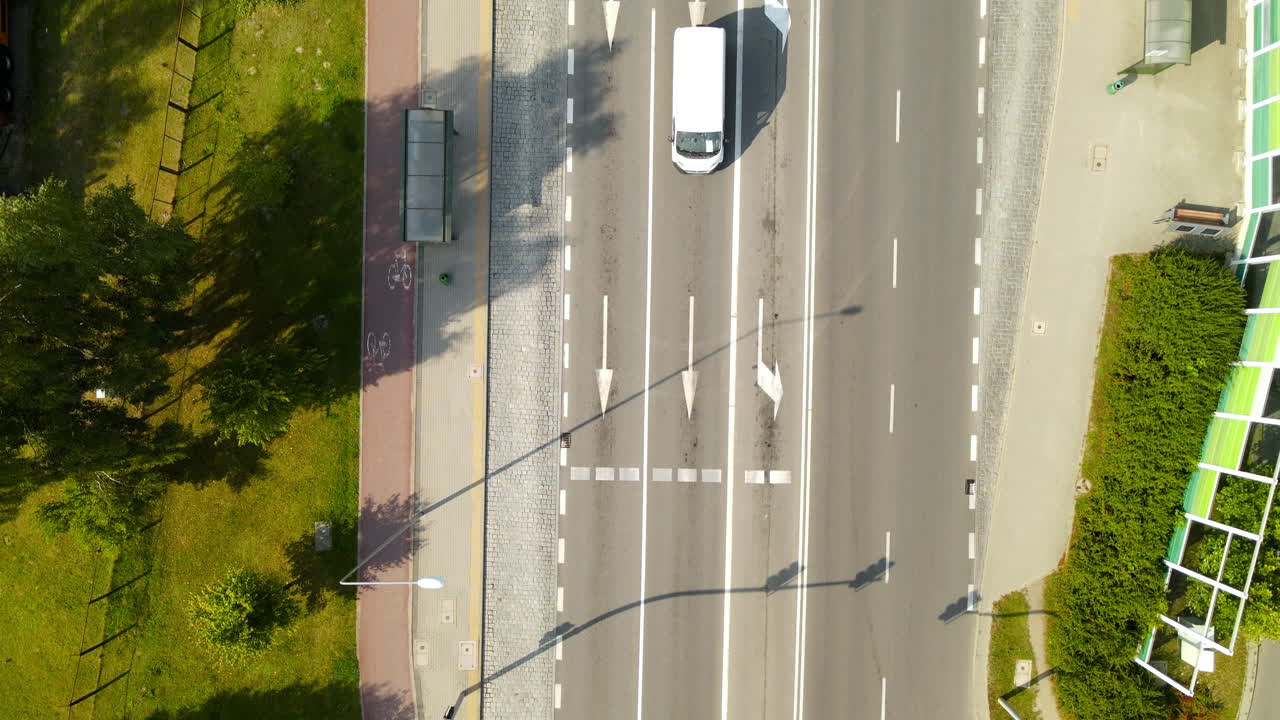 vista superior de la carretera de hormigón con líneas rotas blancas, flecha recta, flecha izquierda y marcas longitudinales que van al parque forestal witomino en gdynia, pomorskie, polonia - toma aérea de drones