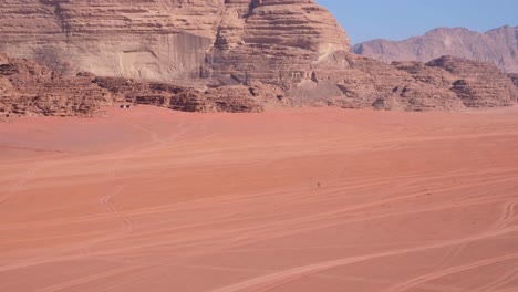 solo person walking and hiking through the desert of wadi rum in jordan, middle east, with vast red sandy landscape