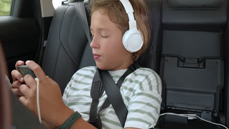 boy with headphones using smartphone in car