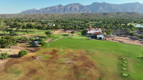 brown golf course being watered by irrigation system in hot and dry desert