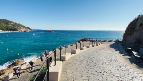 tossa de mar bay seen from the castle to the beach with coarse sand and turquoise blue sea water old walled medieval village fishing village mediterranean sea walking along the promenade