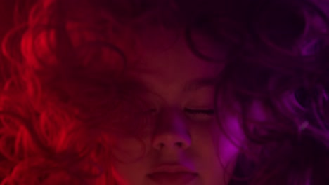 artistic portrait of girl behind colored glass with dramatic lighting close up portrait of a girl viewed through tinted or reflective glass illuminated by red green and golden light for a cinematic surreal effect