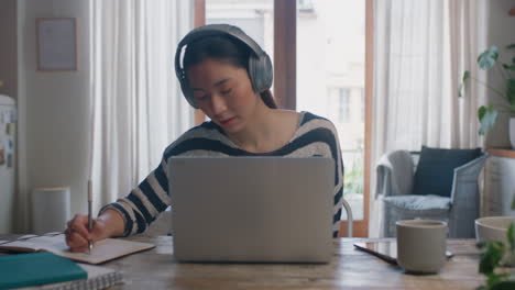 young asian woman using laptop computer working from home student brainstorming project researching information online writing notes enjoying study