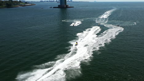 toma aérea y orbita sobre un grupo de motociclistas en las aguas entre brooklyn - staten island, nueva york, con el puente verrazano al fondo