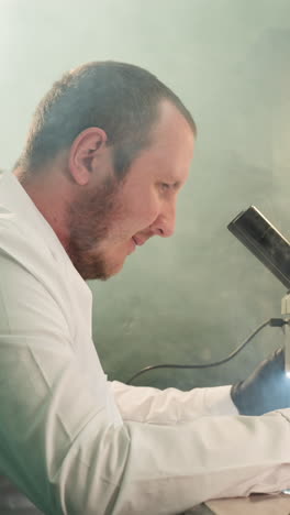 una vista de cerca de un técnico que trabaja en una placa de circuitos electrónicos bajo un microscopio, el espacio de trabajo bien iluminado está lleno de herramientas y equipos, con la lámpara de escritorio encendida