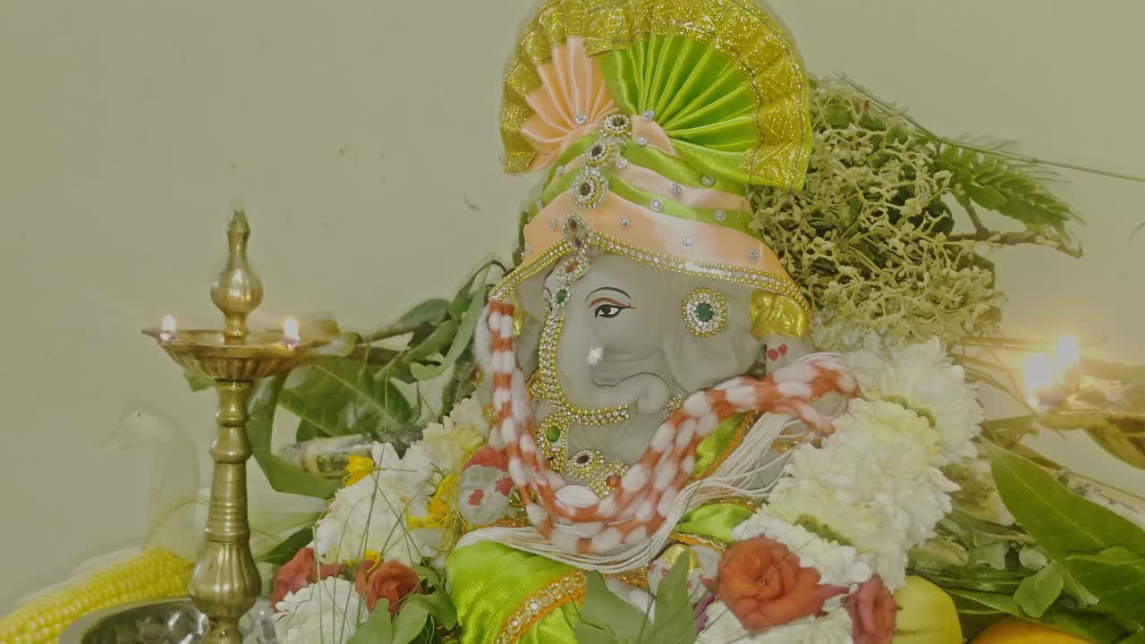 Beautifully decorated Lord Ganesh idol adorned with flowers, garlands, fruits, and traditional oil lamps, representing Indian devotional worship and spirituality. internal shot, close-up shot, 4k