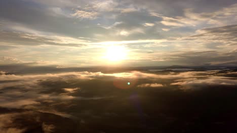 above clouds against sun, aerial drone pan right, flying in the sky