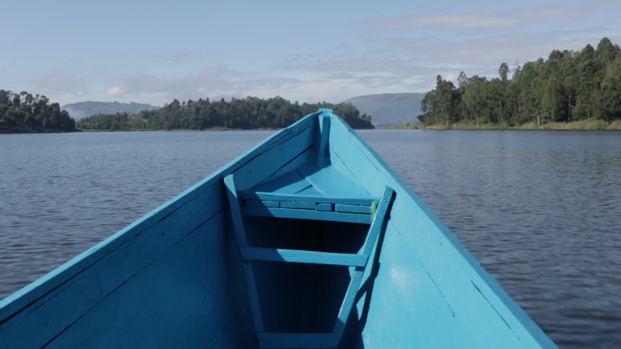 barco de motor azul conduciendo en un río tranquilo en uganda, africa
