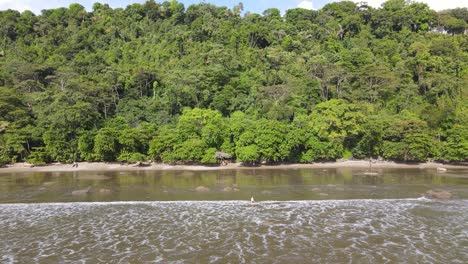 Establish-shot-of-a-lady-sitting-on-a-sand-beach-with-jungle,-Costa-Rica