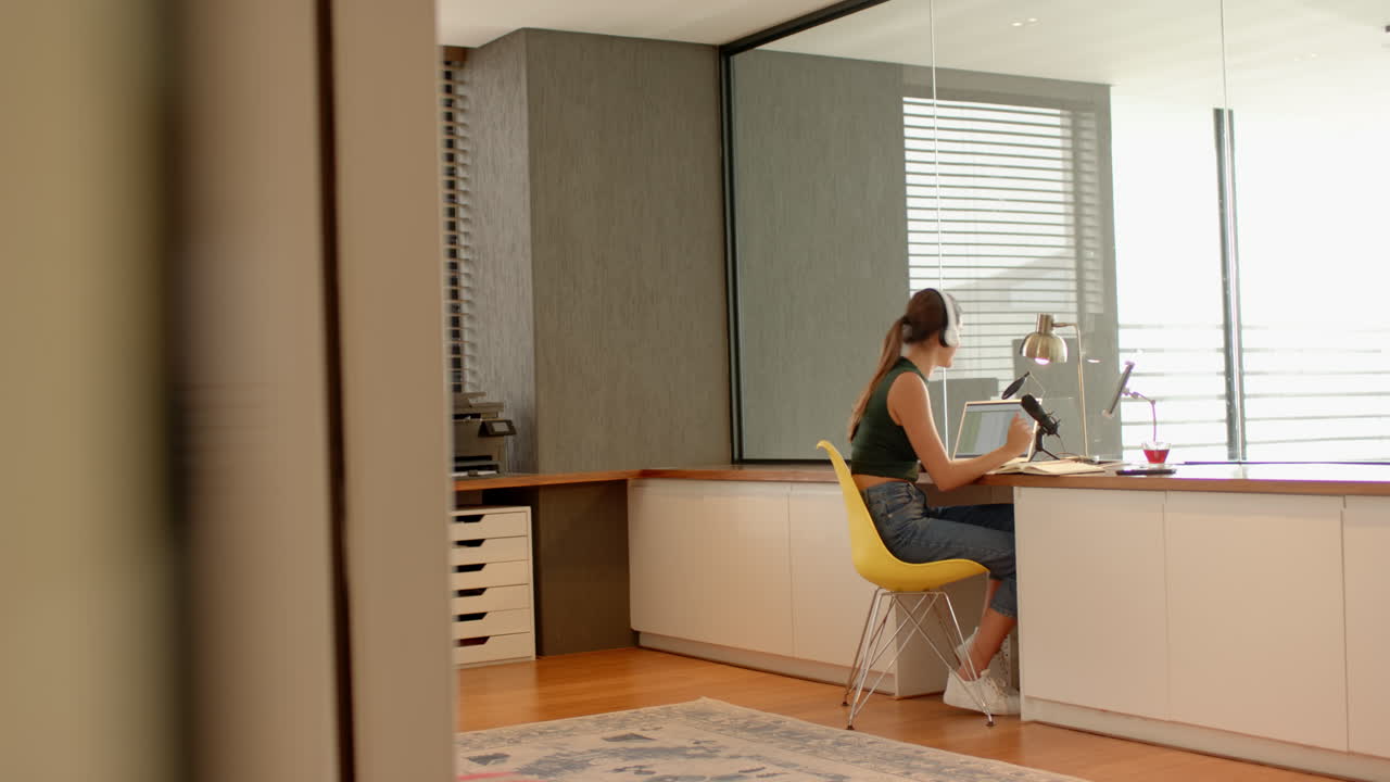 Working from home, woman using laptop and holding coffee cup in modern office