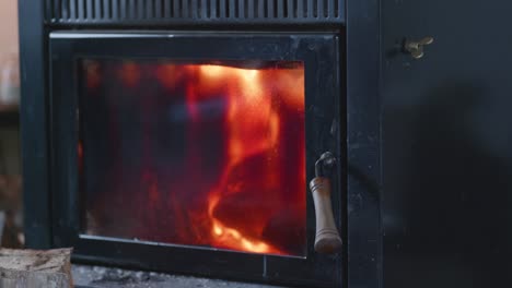 hot, roaring fire behind black, sooty glass door of indoor fireplace