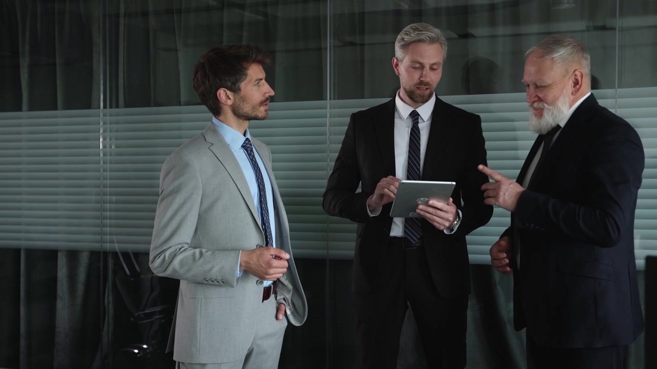 Tre uomini d'affari che discutono informazioni su un tablet in un ufficio.