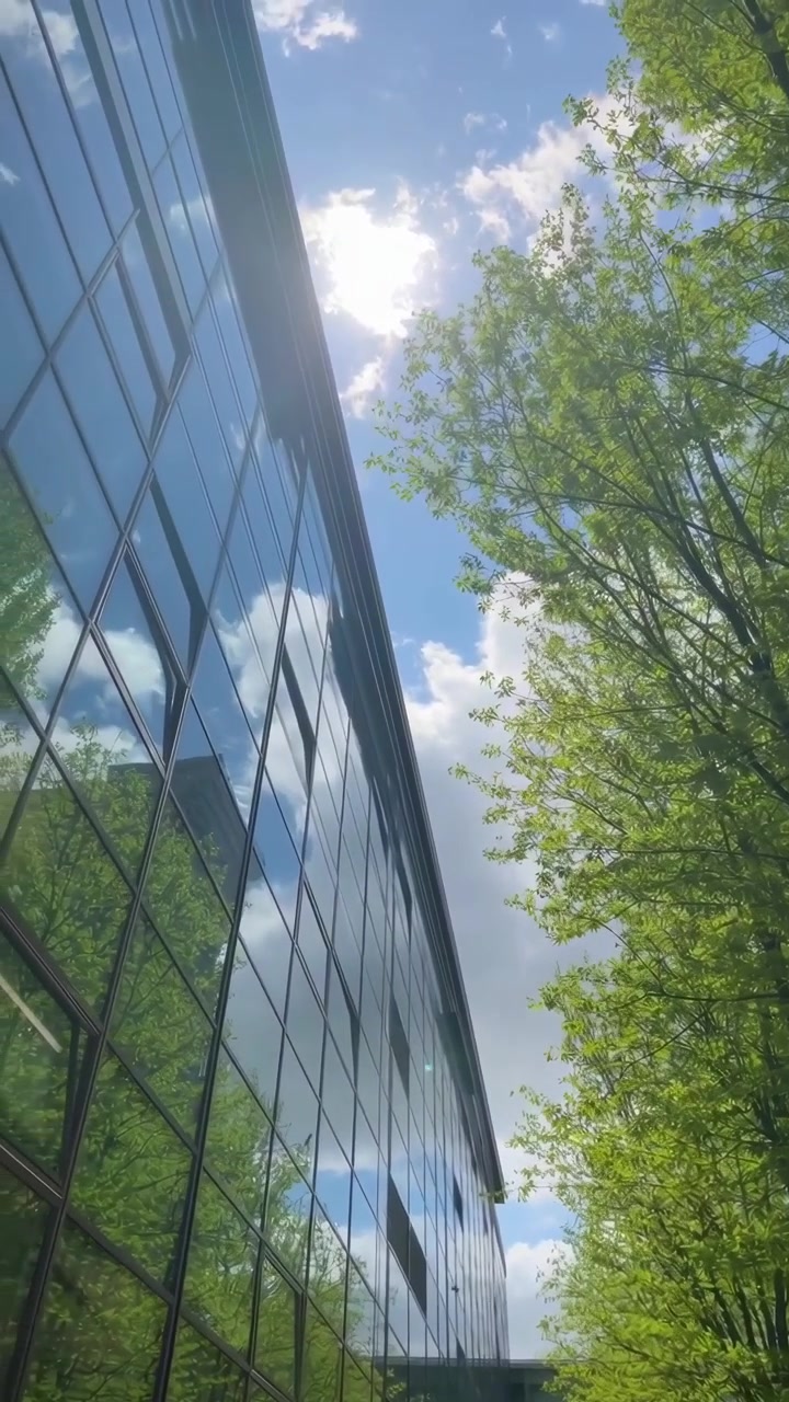Edifício de Escritórios de Vidro Moderno Refletindo o Céu Azul e as Nuvens