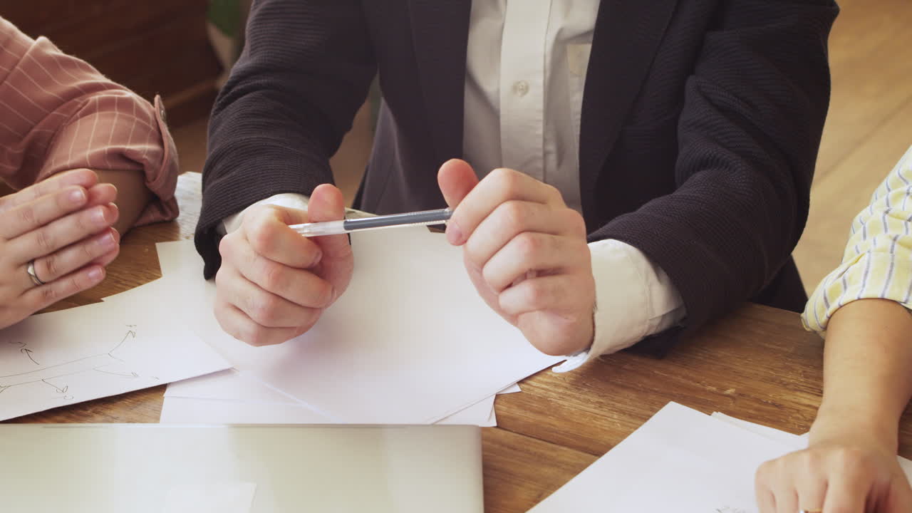 팀 회의 중에 테이블에 앉아 동료들에게 무언가를 설명하는 젊은 전문직 여성