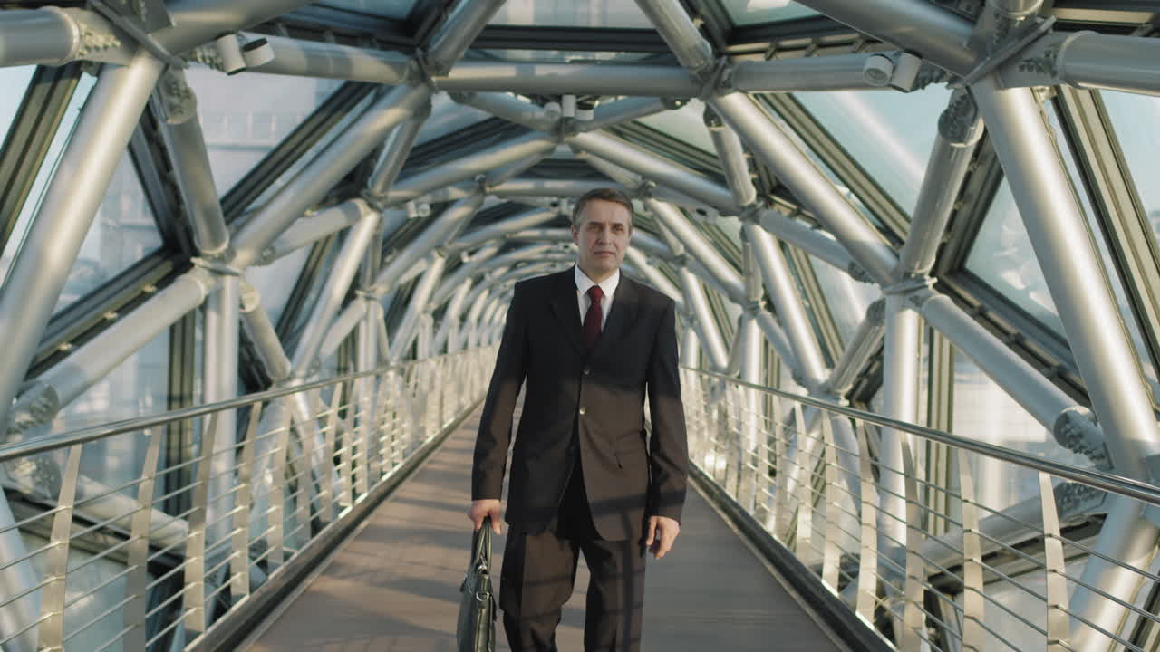 Middle-Aged Business Man Walking Along Glass Bridge