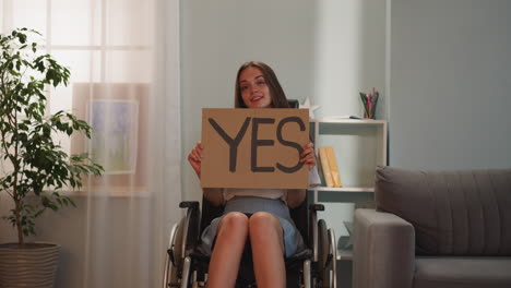 una mujer discapacitada alegre gira un cartel con la palabra sí a la cámara