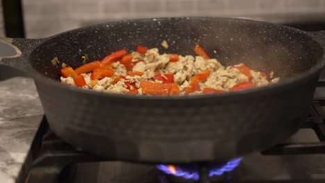 steam rising from sausage and red peppers cooking on a stove