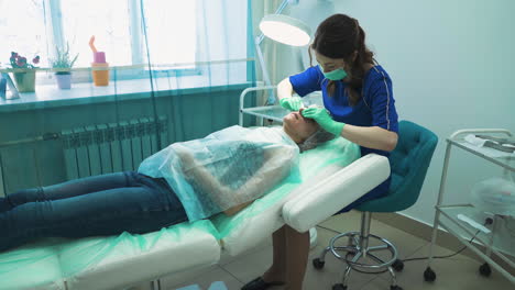 esteticista con máscara protectora aplasta las espinillas del cliente