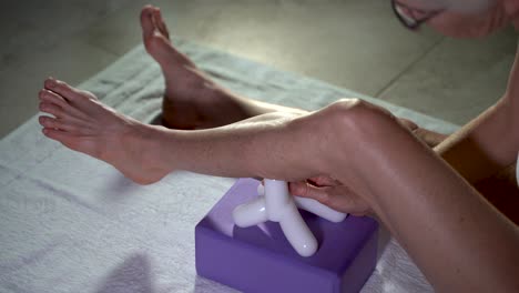 Overhead-closeup-view-of-mature-woman-using-a-massage-tool-for-myofascial-therapy-on-her-leg’s-calf