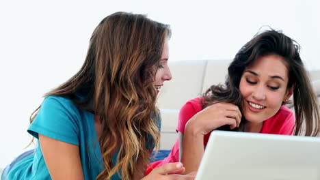 mujeres atractivas y divertidas usando un cuaderno tendido en el suelo