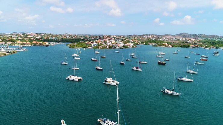Panoramica aerea in movimento su catamarani a vela ancorati nella baia caraibica delle Spanish Waters, Curaçao