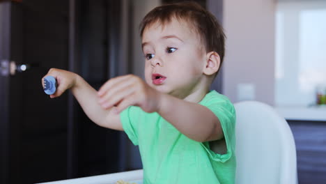 beautiful little kid licks the fork. baby notices something and asks for it with gestures. blurred backdrop.