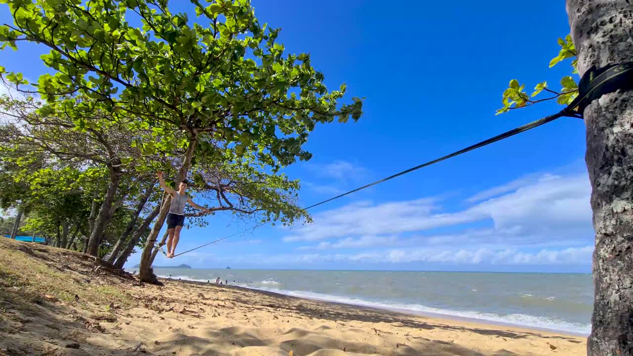 macho adulto joven en slackline en trinity beach en cairns