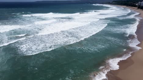 una costa serena con olas acariciando arenas doradas, vista aérea