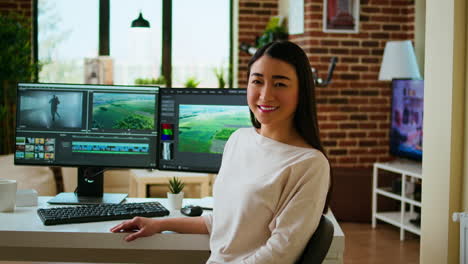 Asian-woman-video-editor-working-with-dual-monitors-in-living-room