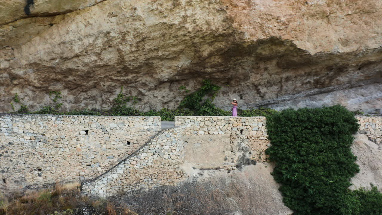 Aéreo de afastamento de jovem mulher passeando com seu cachorro ao longo do Mirador al Puente Romano Guadalajara.