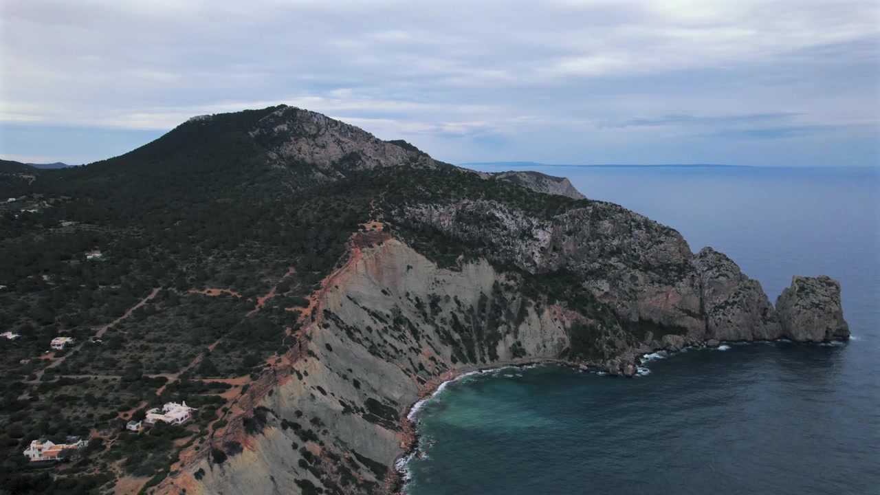 Ripresa aerea in 4K con drone di Cap Blanc a Ibiza, Spagna. Scogliere rocciose spettacolari, acque cristalline del Mediterraneo e vista verso l'iconica isola di Es Vedrà creano un paesaggio costiero mozzafiato