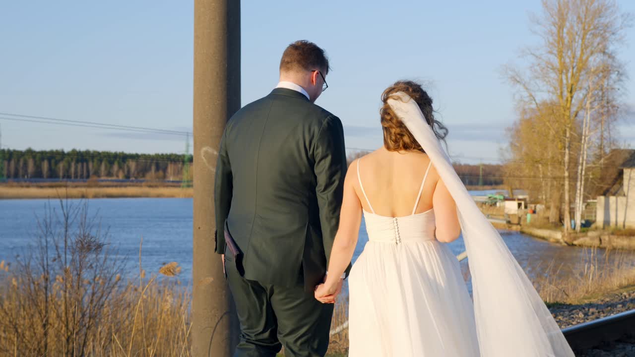 Just married family walking near water pond, back view