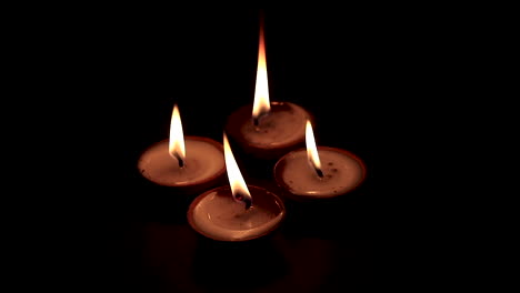 four  butterlamp candles burning in the dark. traditional butterlamp glowing in the dark