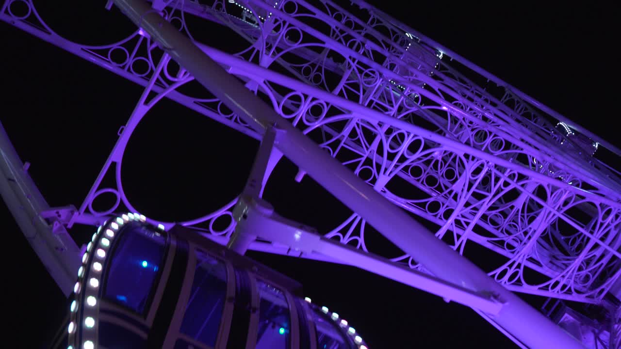 The beautiful purple glow of a ferris wheel in Granada, Spain - tilt up