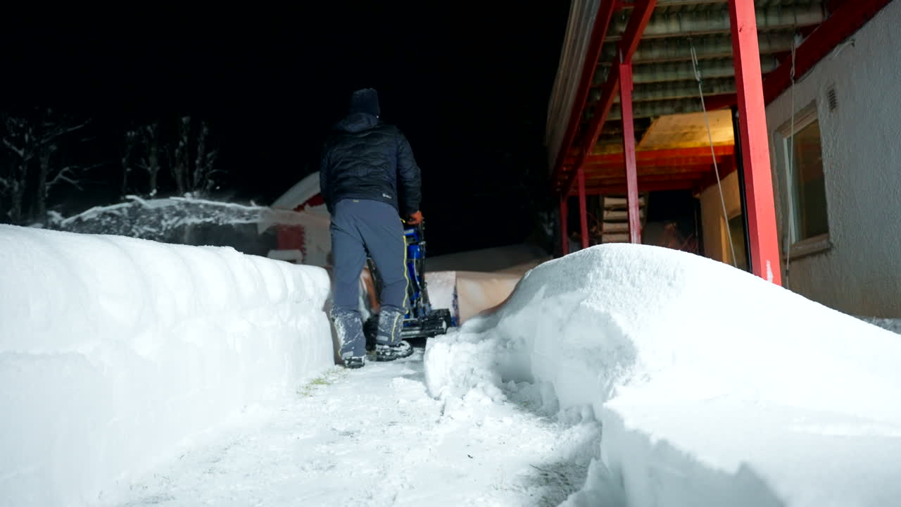 Young Norwegian man clearing path alongside building exterior