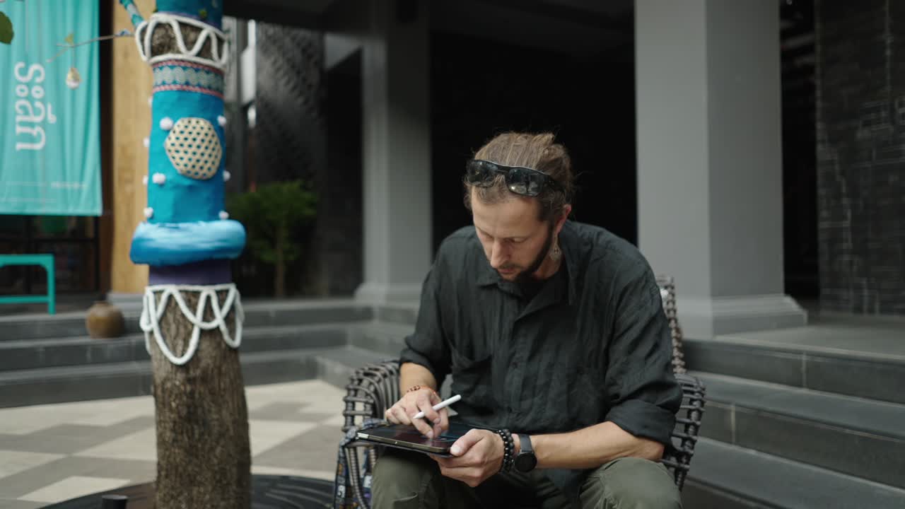 Man drawing on a tablet with a stylus outdoors