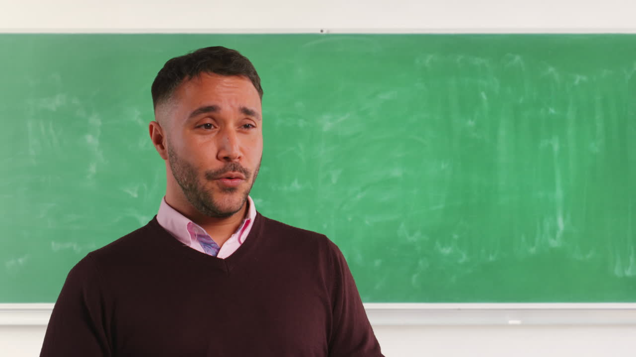 Close Up Shot Of Mature Male Teacher In Classroom Standing In Front Of Board Teaching Lesson